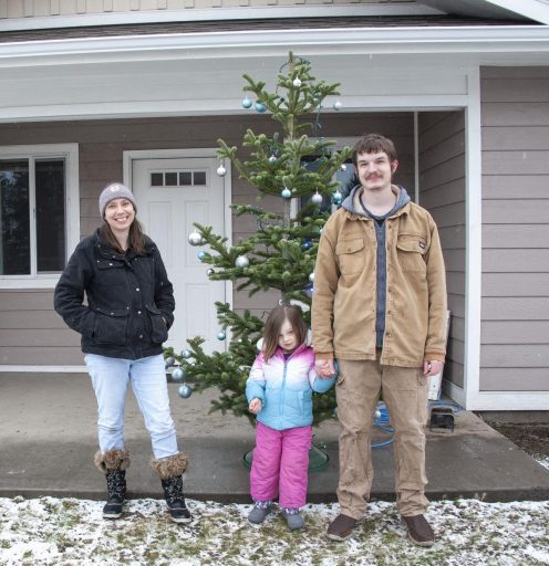 The Leaseburgs stand out front of their new home with a Christmas Tree