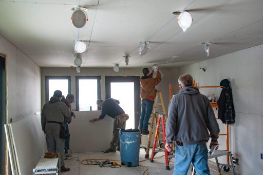 Volunteers finish the drywall installation at the build site.